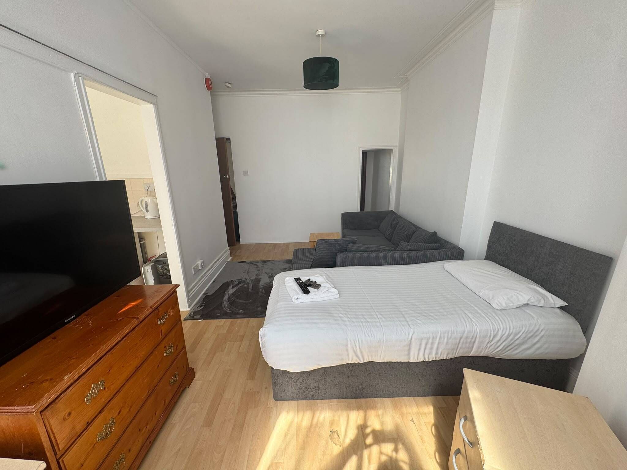 Una habitación de hotel con cama, televisor, cómoda y kitchenette.