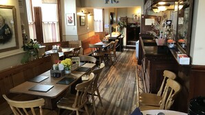 A restaurant interior with wooden tables and chairs, a bar area, and a sign reading "BAR A BWYTYR FIC". - Victoria Guest Accommodation & Studio Apartments (Pwllheli)