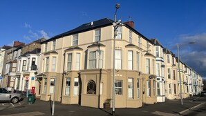 A row of terraced houses with a central building featuring a plaque. - Victoria Guest Accommodation & Studio Apartments (Pwllheli)