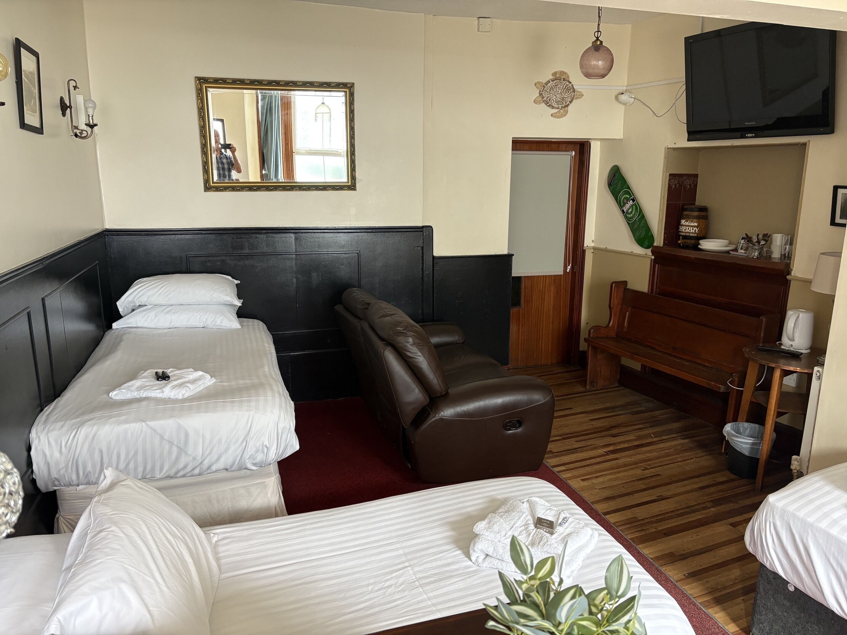 Una habitación de hotel con cama, sofá, televisor y una pequeña mesa con una planta.