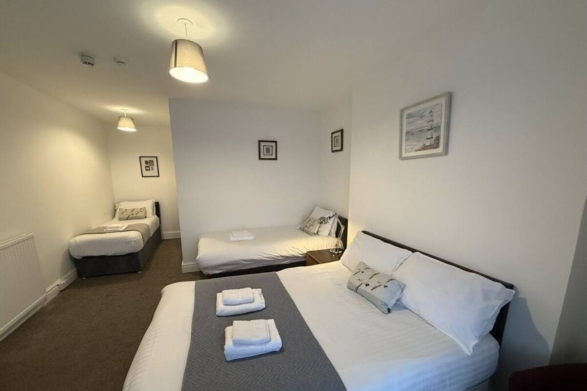 A hotel room with a large bed, two smaller beds, a sitting area, and a red chair.