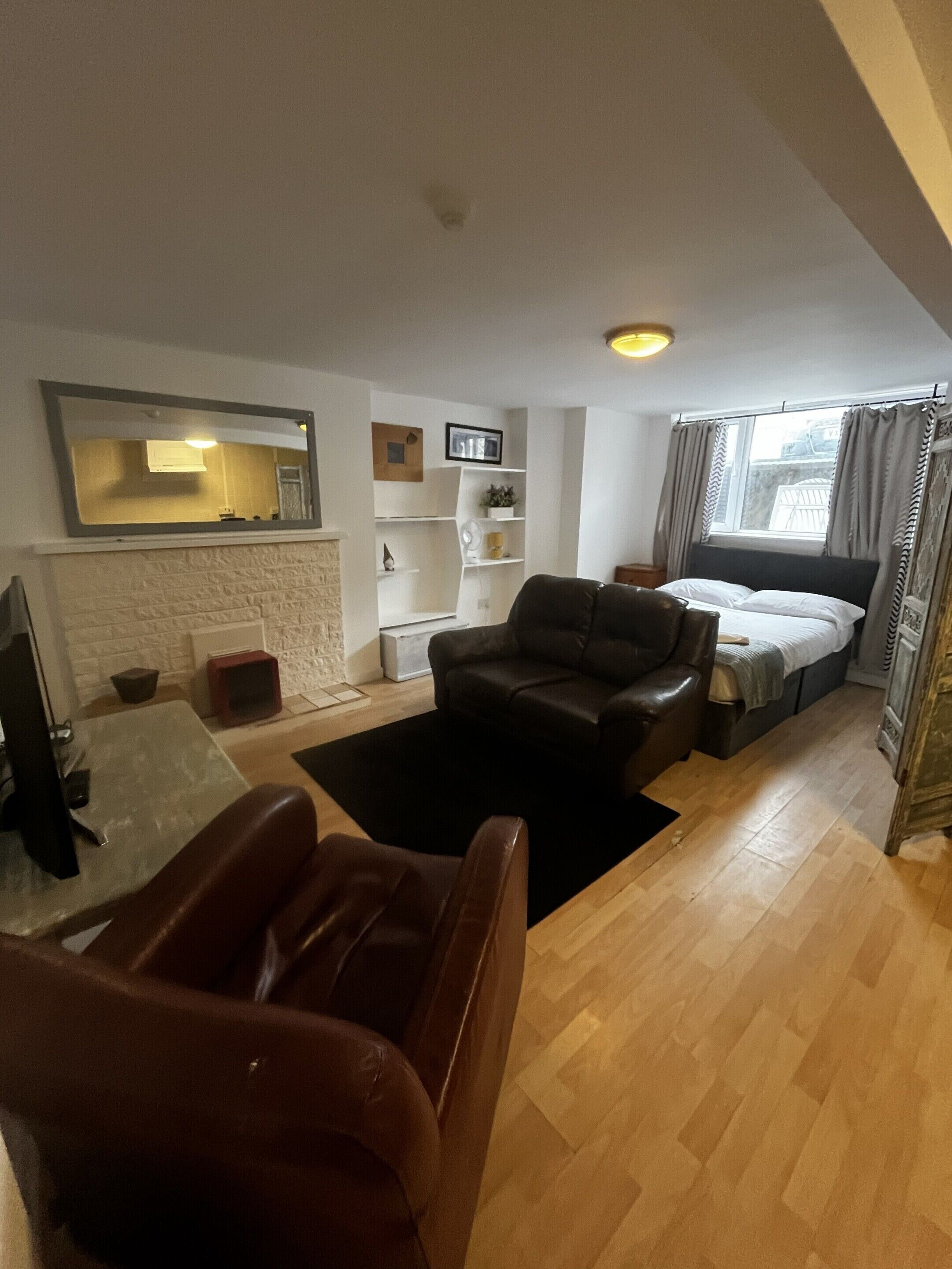 A compact living space with a sofa, a small table, a bed, and a fireplace.