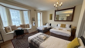 A hotel room with two beds, a sofa, a dining table, and a large mirror. - Victoria Guest Accommodation & Studio Apartments (Pwllheli)