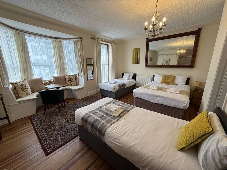 A hotel room with two beds, a sofa, a dining table, and a large mirror.