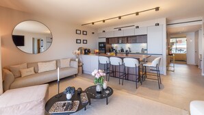 Ein modernes Wohnzimmer mit einer Couch, einem Couchtisch und einer Küchenzeile mit Barhocker.