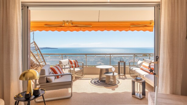 Ein Balkon mit Meerblick, ausgestattet mit einer Couch, Stühlen und einem Tisch.