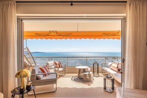 Un balcon avec vue sur la mer, aménagé avec un canapé, des fauteuils et une table.