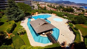 Ein Resort mit einem großen Schwimmbad, überdachtem Bereich und Blick auf die Stadt und die Berge im Hintergrund.
