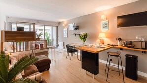 Un salon moderne comprenant un canapé, une table à manger et un coin cuisine avec un tabouret de bar.