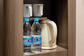 A wooden cabinet with two water bottles and a coffee maker. - Hilbert Hotel (Guangzhou Nansha Wanda Plaza Jinzhou Subway Station) (Guangzhou)