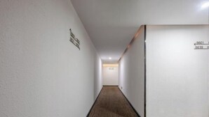 A narrow hallway with a wooden floor and white walls, leading to a room with a door marked 8601. - Hilbert Hotel (Guangzhou Nansha Wanda Plaza Jinzhou Subway Station) (Guangzhou)