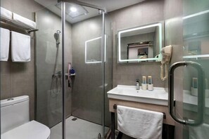 Enjoy a refreshing shower in the bathroom, featuring a glass-enclosed shower, sink, and toilet.