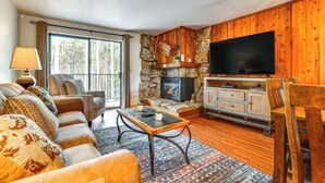 A cozy living room with a stone fireplace, comfortable seating, and a flat-screen TV. - Winter Park Condo w/ Resort Shuttle On-Site! (Winter Park)