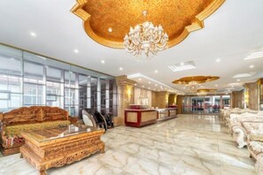 A spacious lobby with a reception desk, seating area, and a chandelier.