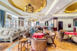 A spacious hotel lobby with a grand chandelier, plush seating, and a view of the city.
