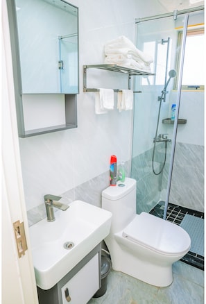 Een moderne badkamer met een douchecabine van glas, een wit wastafelmeubel en een toilet.