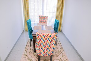 Een eethoek met een tafel en stoelen, een patroon kussen en een vloerkleed.
