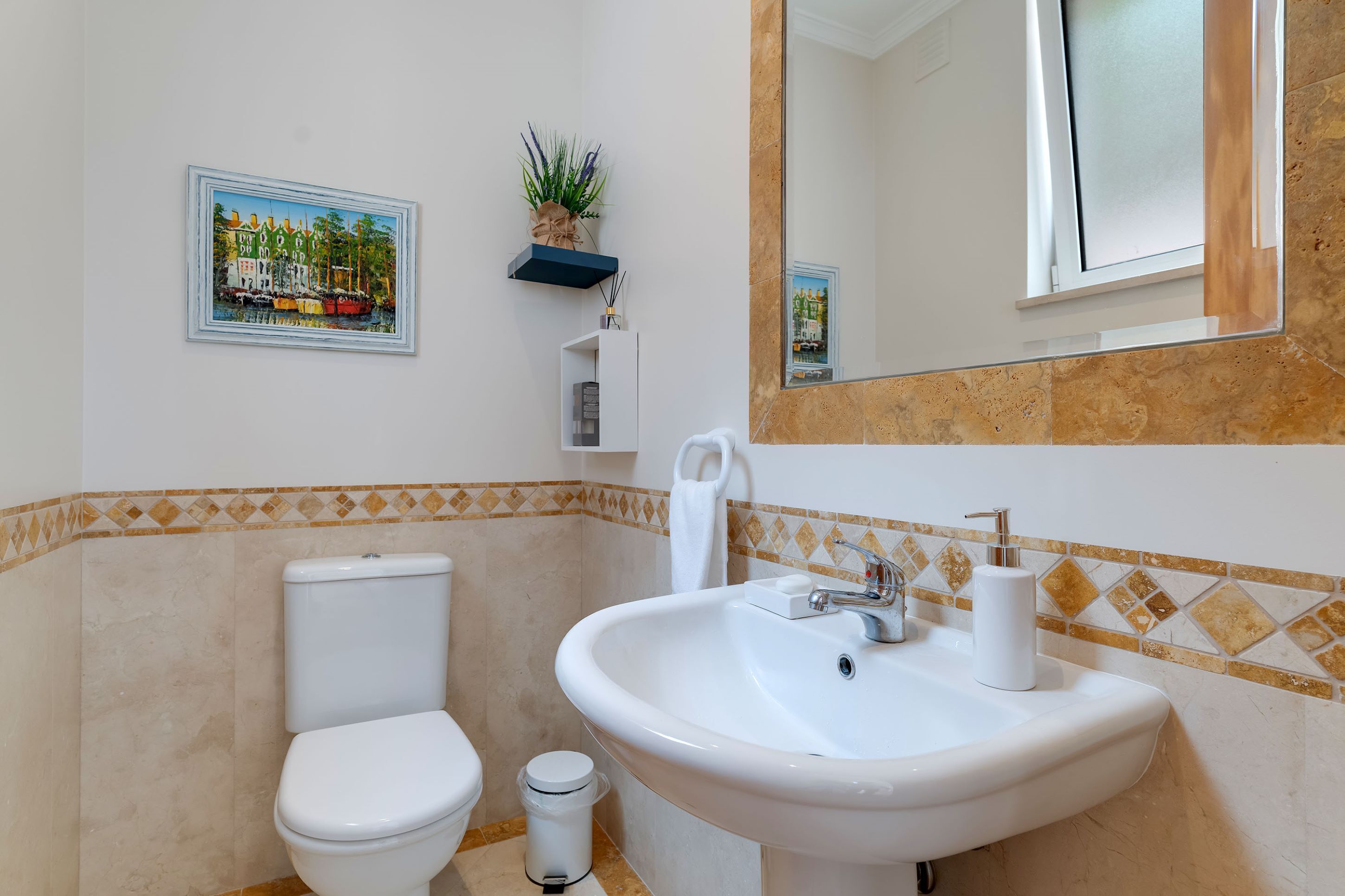 Un bagno con il water, un lavandino e un quadro appeso alla parete.