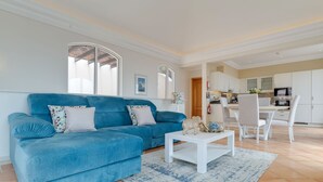 A living room with a blue sofa, white coffee table, and a patterned rug. - Villa Sol Palheiro Village (Funchal)