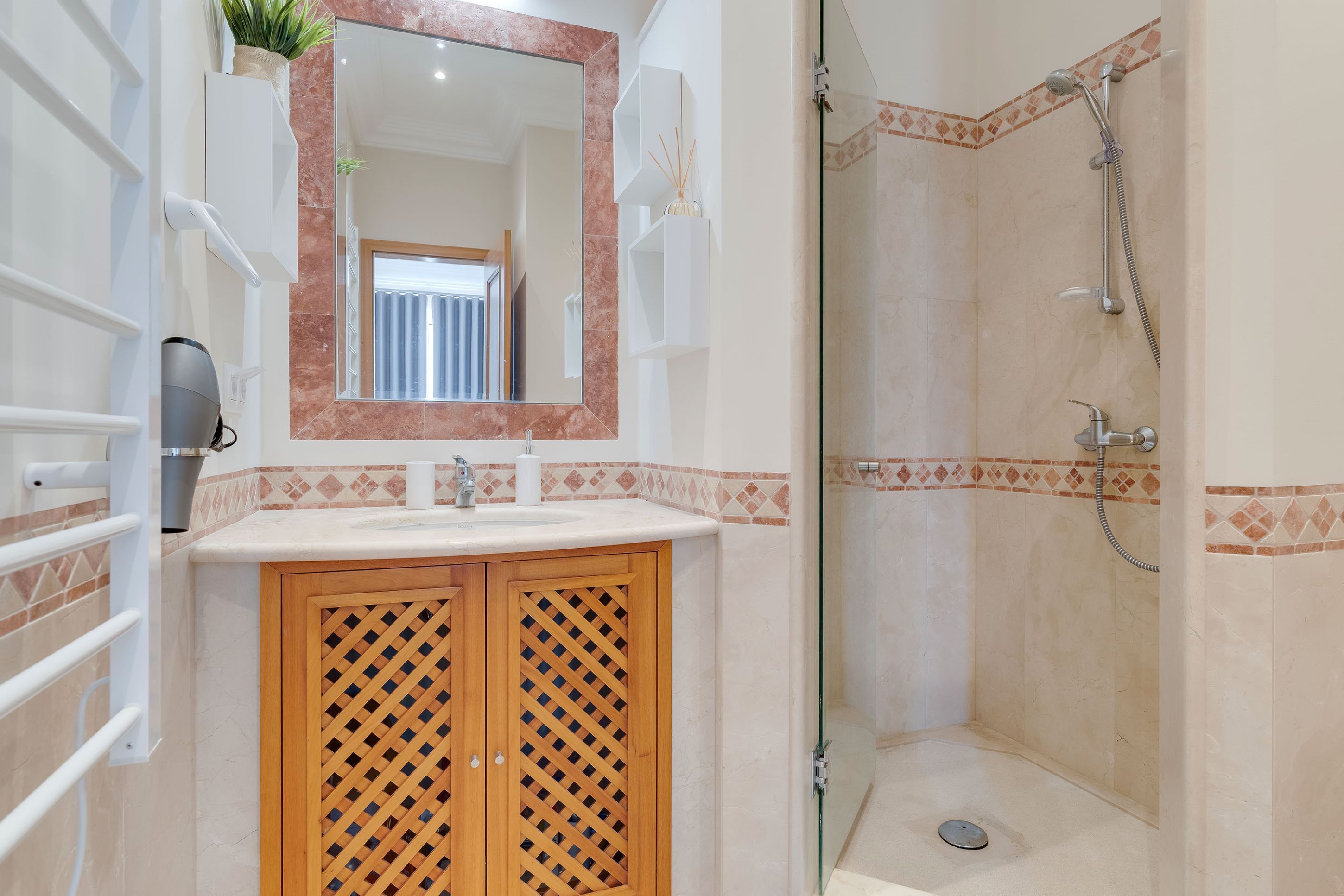 A bathroom with a sink, mirror, and shower.