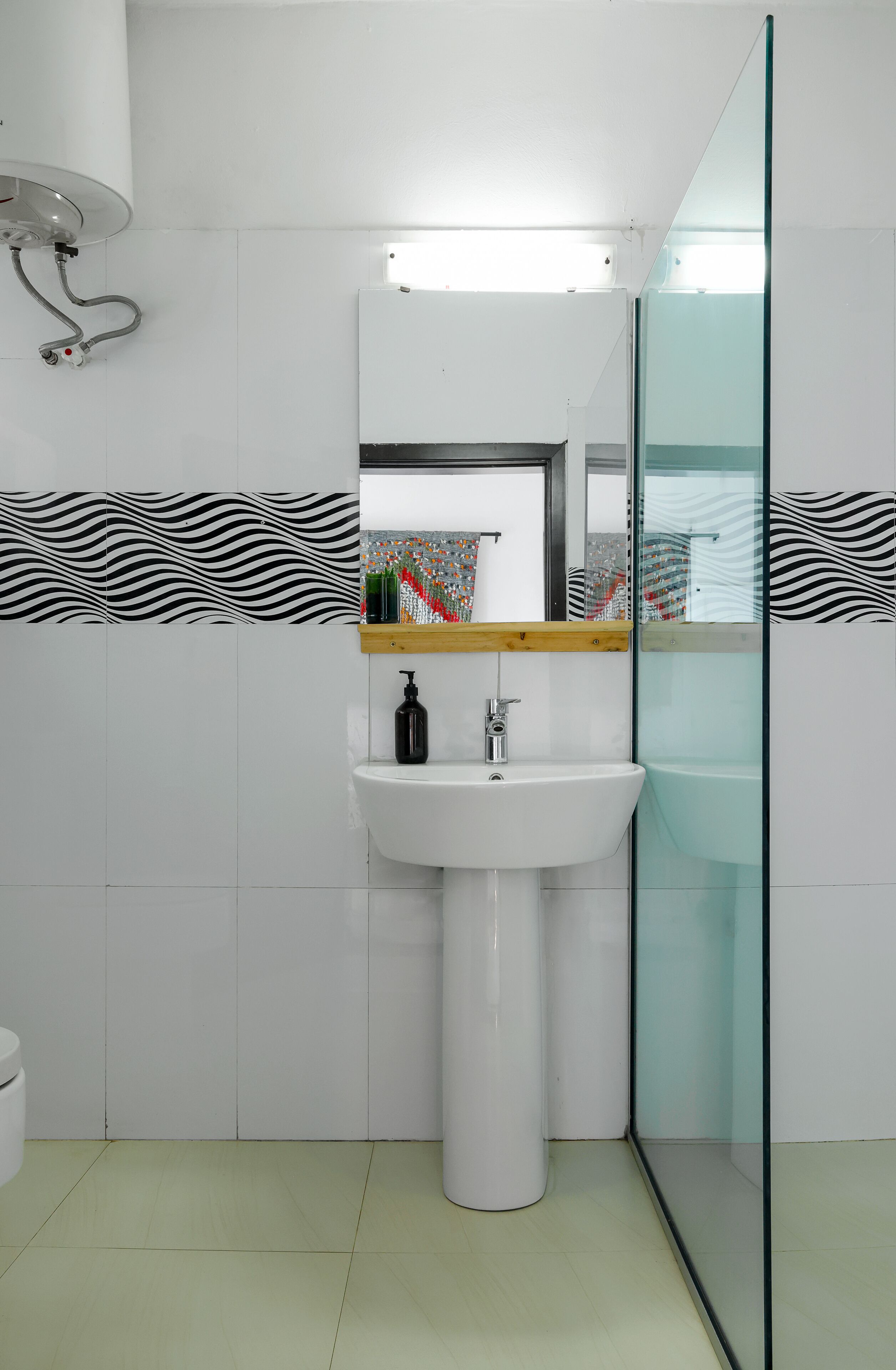Une salle de bain moderne avec un lavabo blanc, une douche en verre et un mur recouvert de carreaux à motifs.
