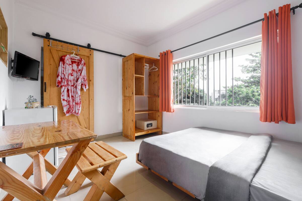 A room with a bed, a wooden table, a TV, and a sliding wooden wardrobe.