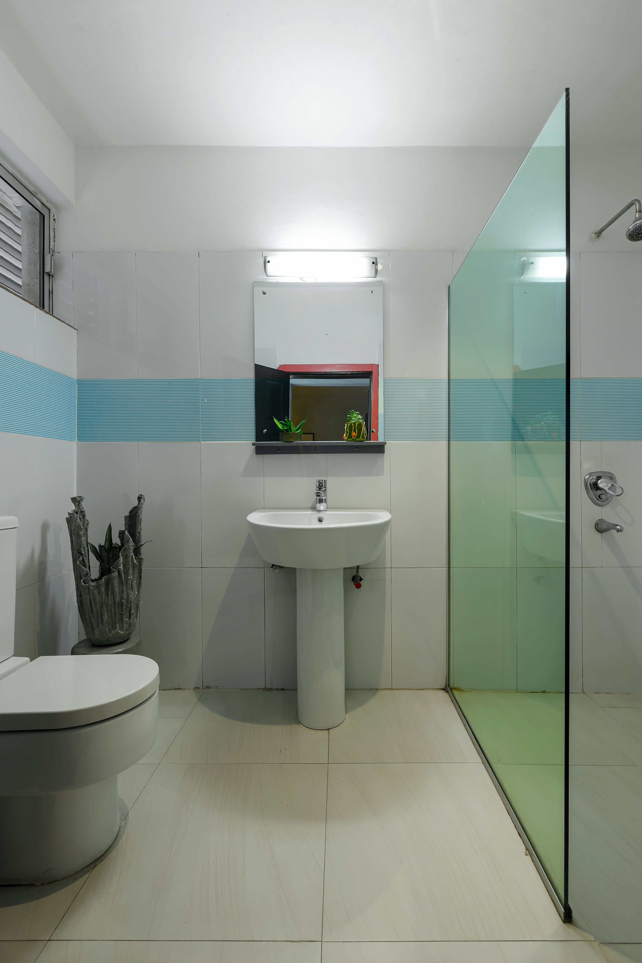 Une salle de bain équipée de toilettes, d’un lavabo et d’une douche à parois en verre.