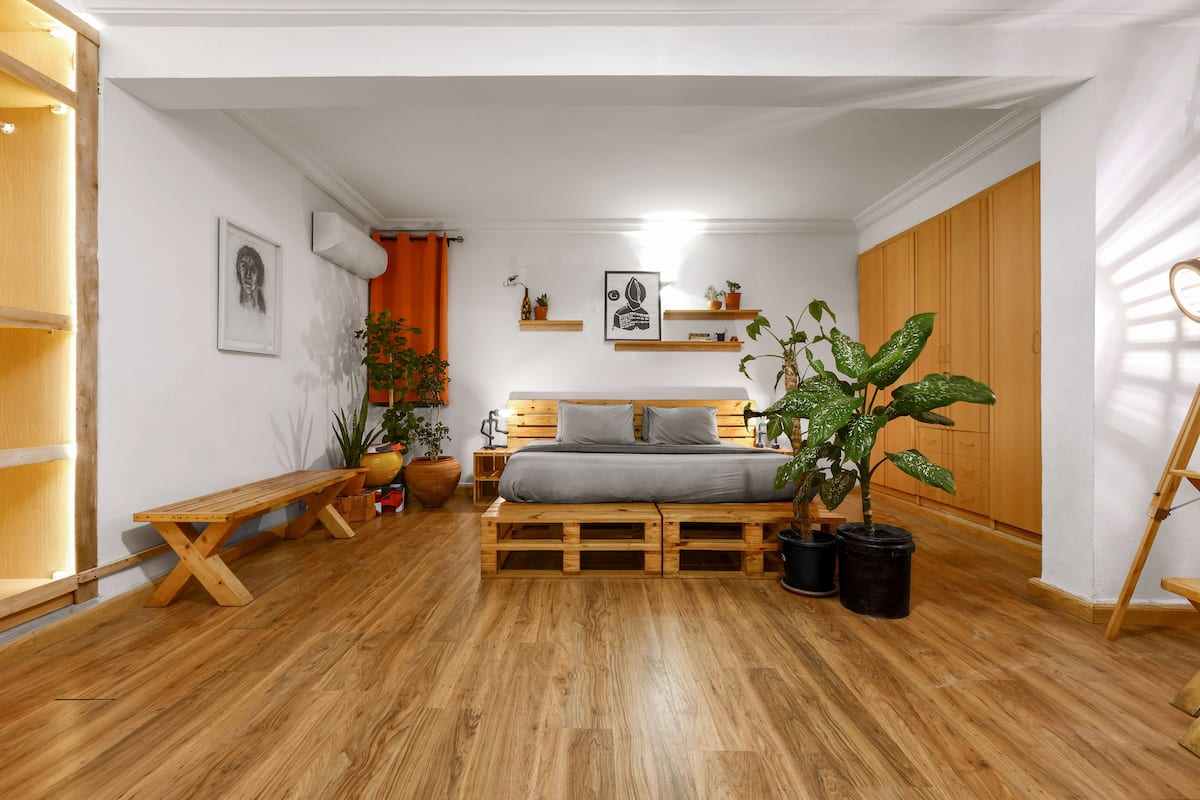 A bedroom with a wooden bed, a bench, and potted plants.