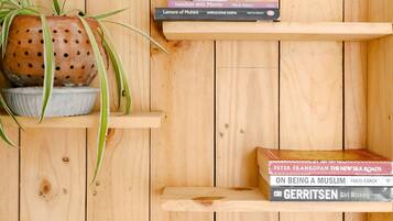 A wooden shelf with a potted plant, a rolled-up towel, and a stack of books.