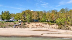 A beach with a sandy shore, a small waterfall, and a forested area with cabins. - Breathtaking Panoramic Views! Lake Huron & Lex! (Lexington)