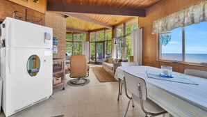 A cozy kitchen with a refrigerator, a dining table, and a window overlooking the sea. - Breathtaking Panoramic Views! Lake Huron & Lex! (Lexington)