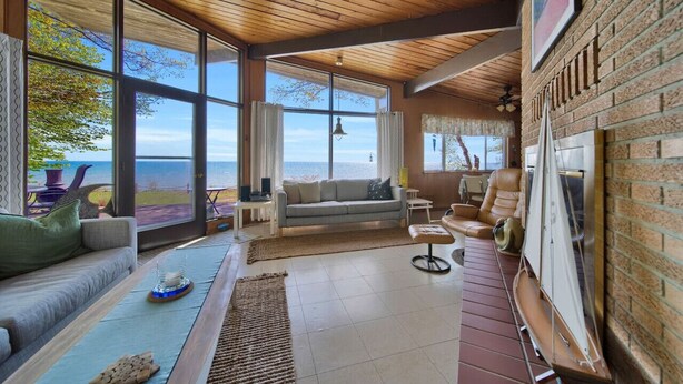 A spacious living area with large windows, a wooden ceiling, and a view of the ocean. - Breathtaking Panoramic Views! Lake Huron & Lex! (Lexington)