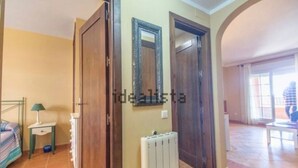 Une pièce comprenant un lit, une petite table de chevet avec une lampe, un radiateur et deux portes.