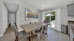 A modern kitchen with a dining area, a large window with curtains, and a view of the outdoors. - Modern Home on Sand Point! 11 mins to DT caseville (Caseville)