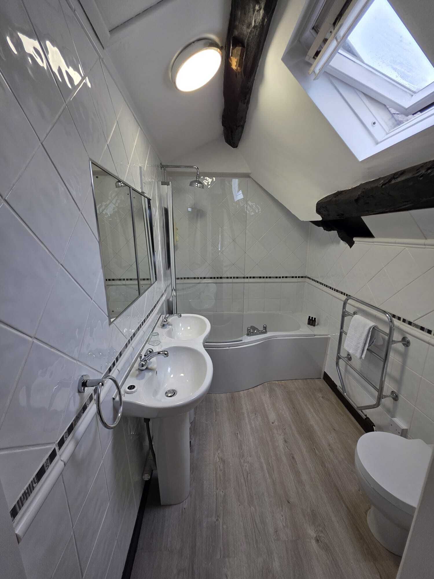 A modern bathroom with two sinks, a bathtub, and a toilet.