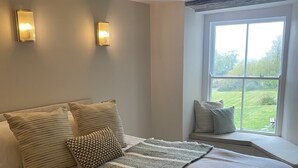 A large bed with a striped blanket, multiple pillows, and two wall-mounted lights. - Maes Y Neuadd Country House (Talsarnau)
