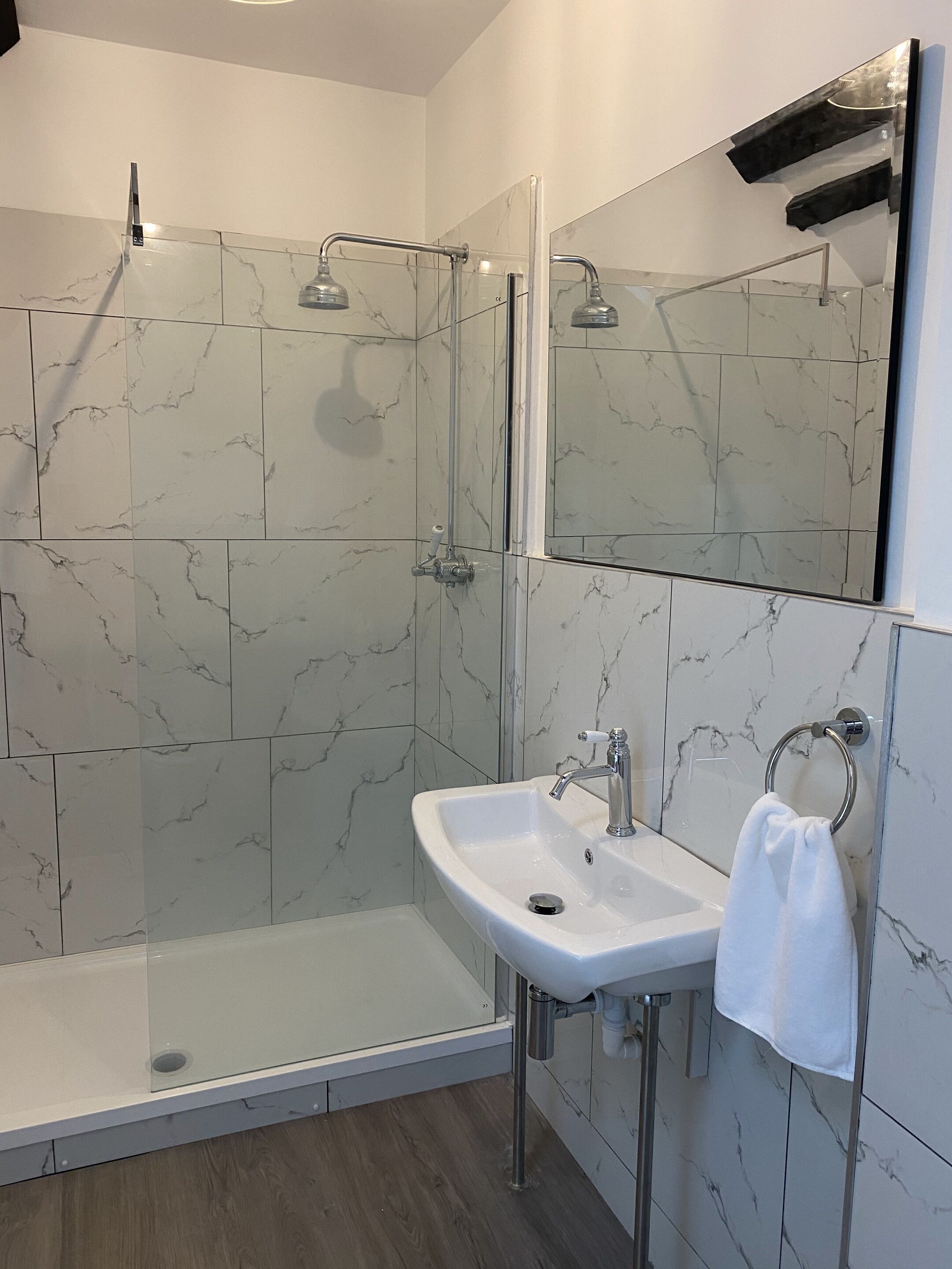 A modern bathroom with a glass-enclosed shower, a white sink, and a large mirror.