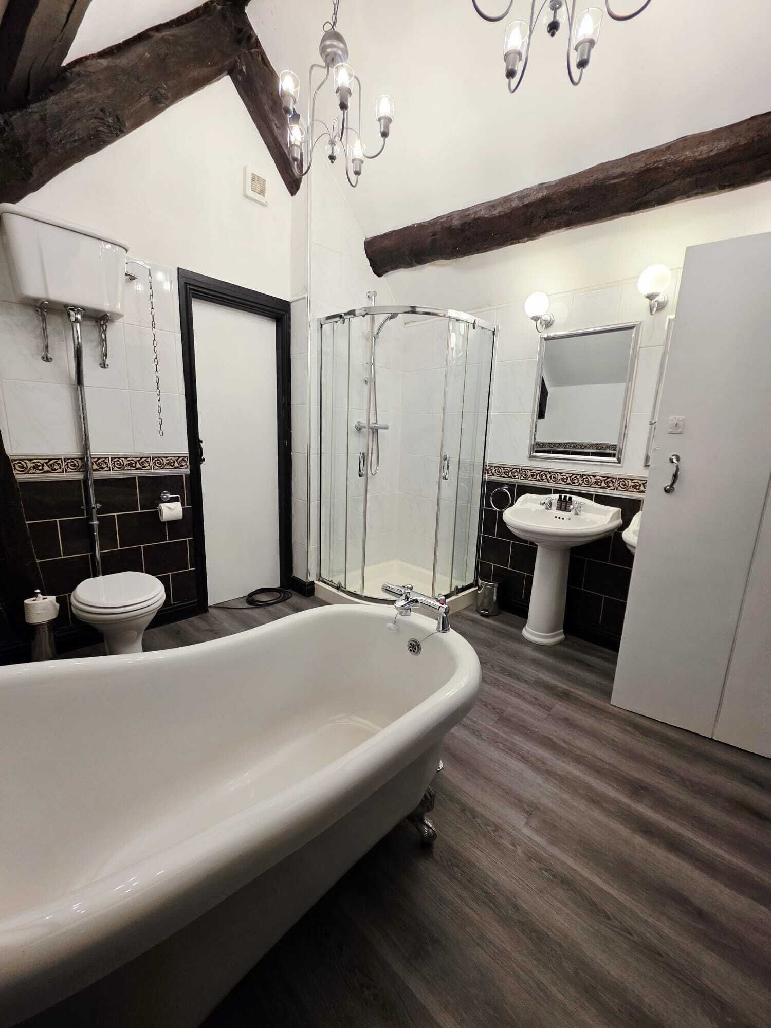 A bathroom with a freestanding bathtub, a glass-enclosed shower, a pedestal sink, and a mirror above the sink.
