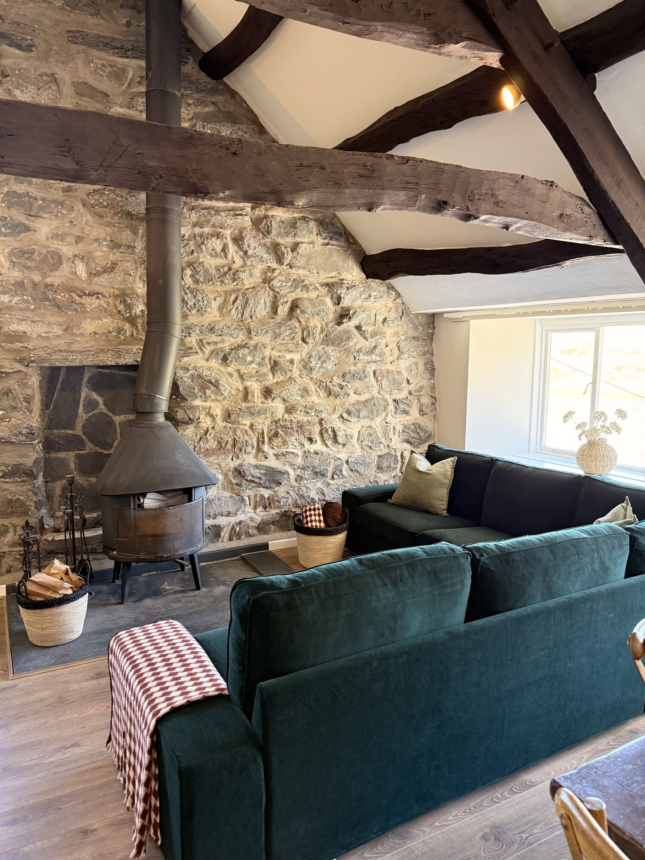 A stone fireplace with a chimney, a green sofa, and a woven basket.