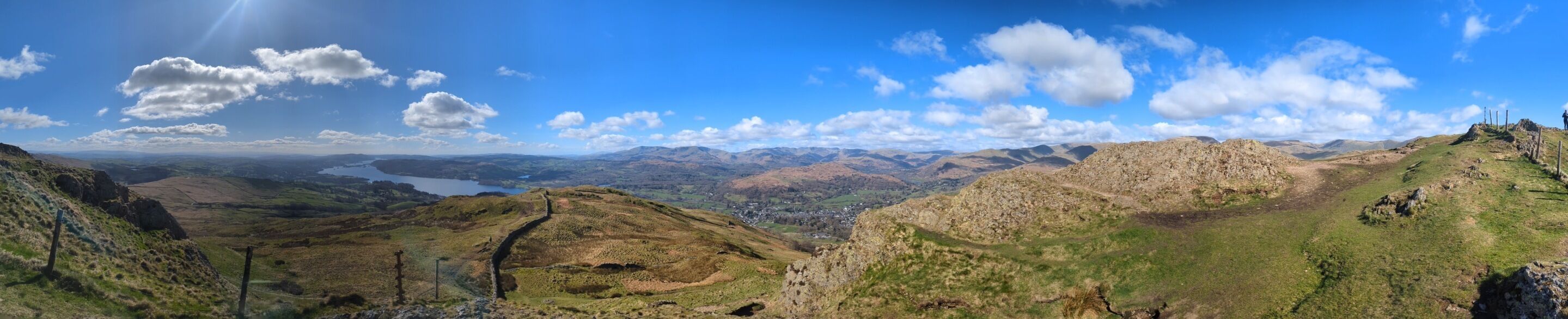 A panoramic view of a mountainous landscape with a lake and distant town.