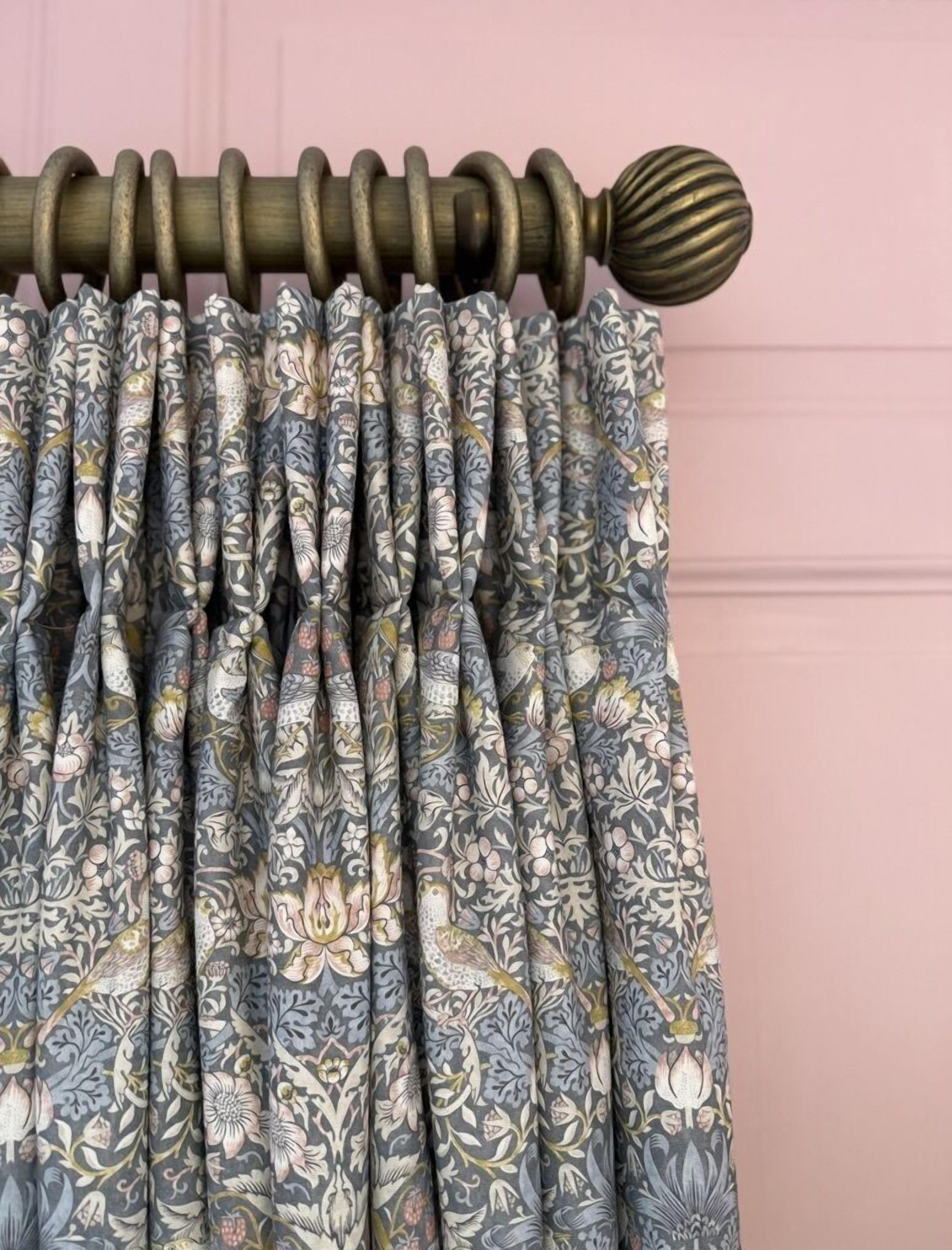 A curtain with a floral pattern and a wooden curtain rod.