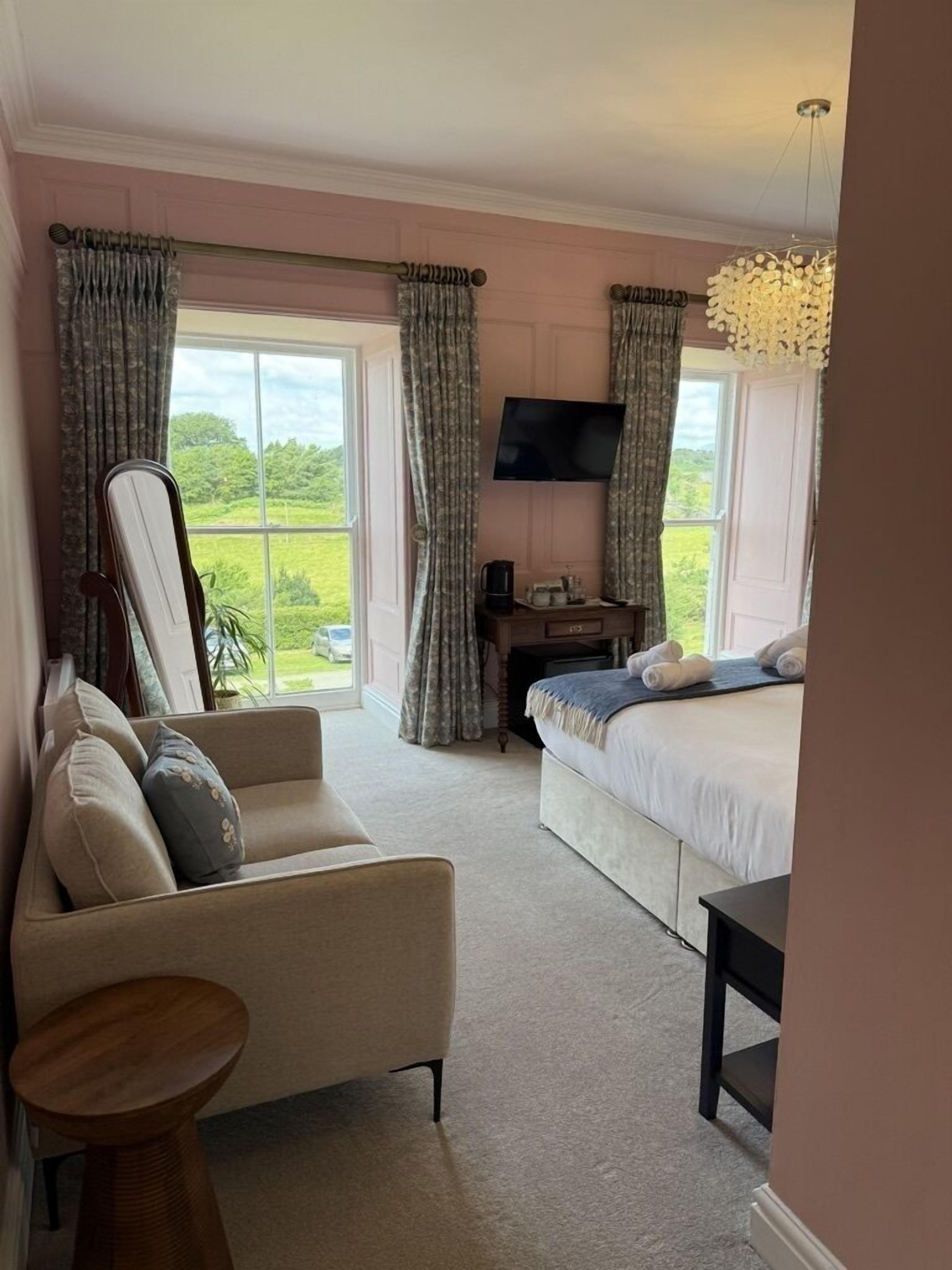A bedroom with a bed, a sofa, a TV, and a desk.