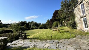 A stone building with a stone pathway leading to a grassy area with a wooden bench. - Maes Y Neuadd Country House (Talsarnau)