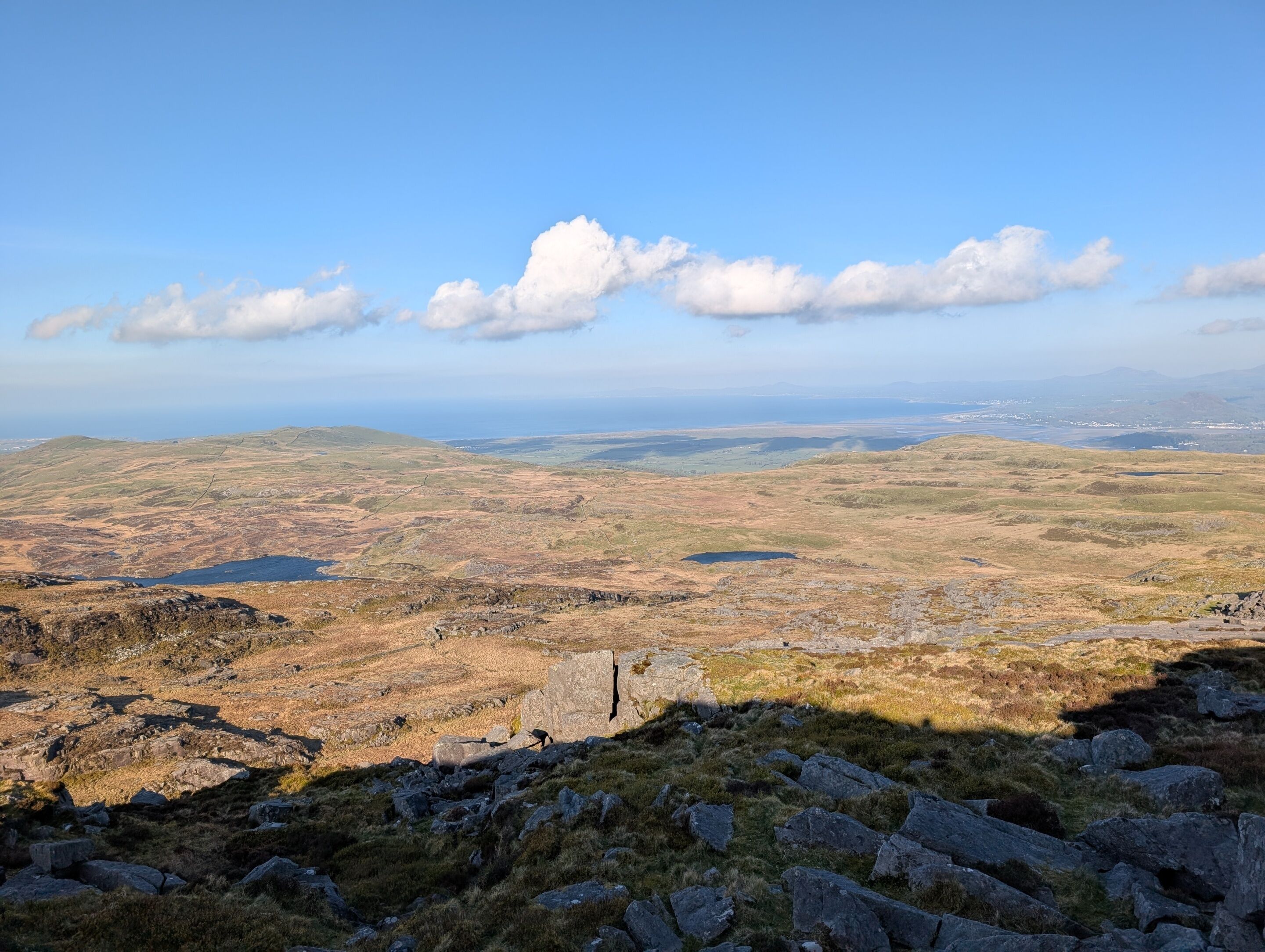 A panoramic view of a hilly landscape with a clear sky and distant mountains.