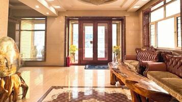 A lobby with a wooden reception desk, a leather sofa, and a patterned rug.