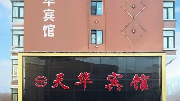 A building with a large sign reading "天华宾馆" (Tianhua Inn) in red characters on a black background.