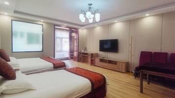 A hotel room with two beds, a TV, a desk, and a seating area.
