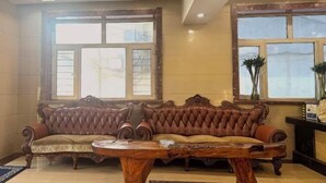 Una habitación con un sofá de cuero marrón, una mesa de centro de madera y grandes ventanales con vistas.