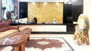 Un área de recepción con un mostrador de mármol, un sofá de cuero, una mesa de centro de madera y una alfombra decorativa.