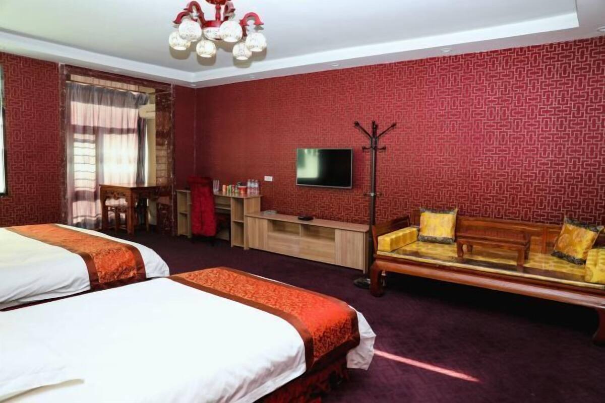 Habitación de hotel con dos camas, un televisor, un sofá y un escritorio con una silla.